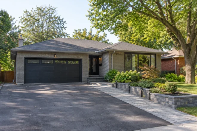Wide asphalt driveway with a separate grey paver route to the bungalow entrance