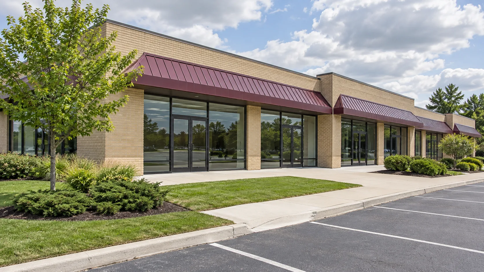 Maintained retail plaza lawn and low beds beside a clear walkway and parking court.