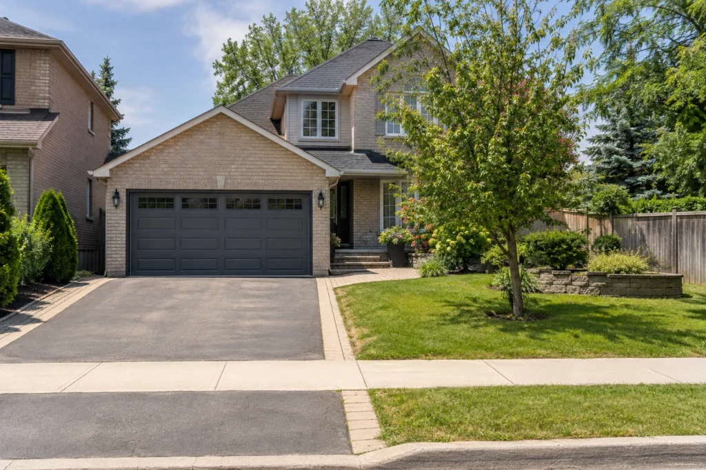 Double garage and asphalt driveway within a light-brick home's front garden